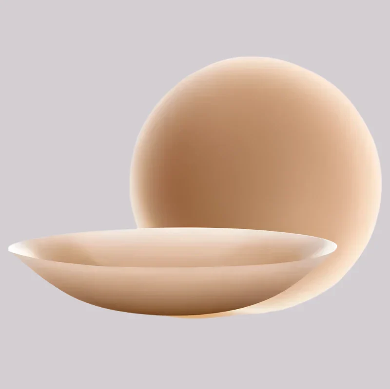 VRCÔMFY warm sand tone adhesive petals featuring anatomical convex form and subtle concave profile | Sculpted curvature with satin-finish surface for second-skin adherence and natural-looking coverage under minimalist slate backdrop